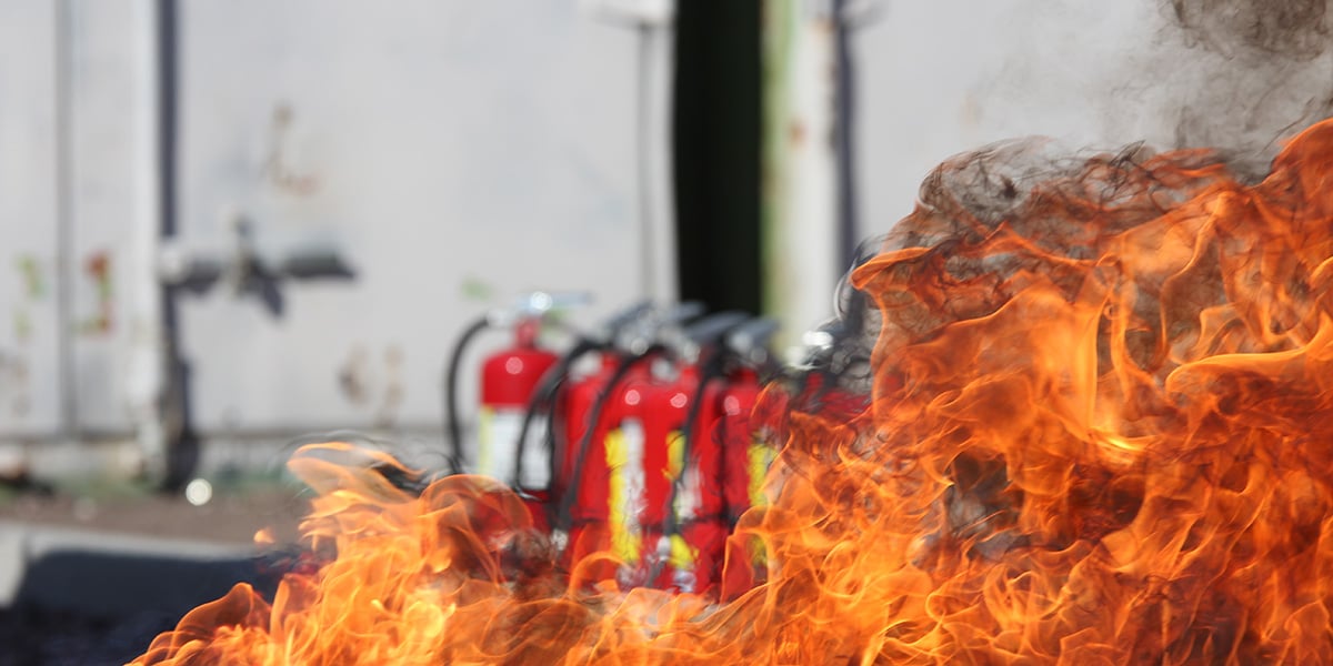 Fire in front of a group of fire extinguishers